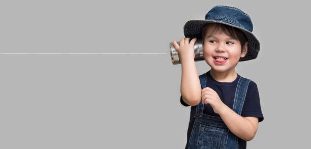 A small boy attached a telephone from a tin can to his ear
